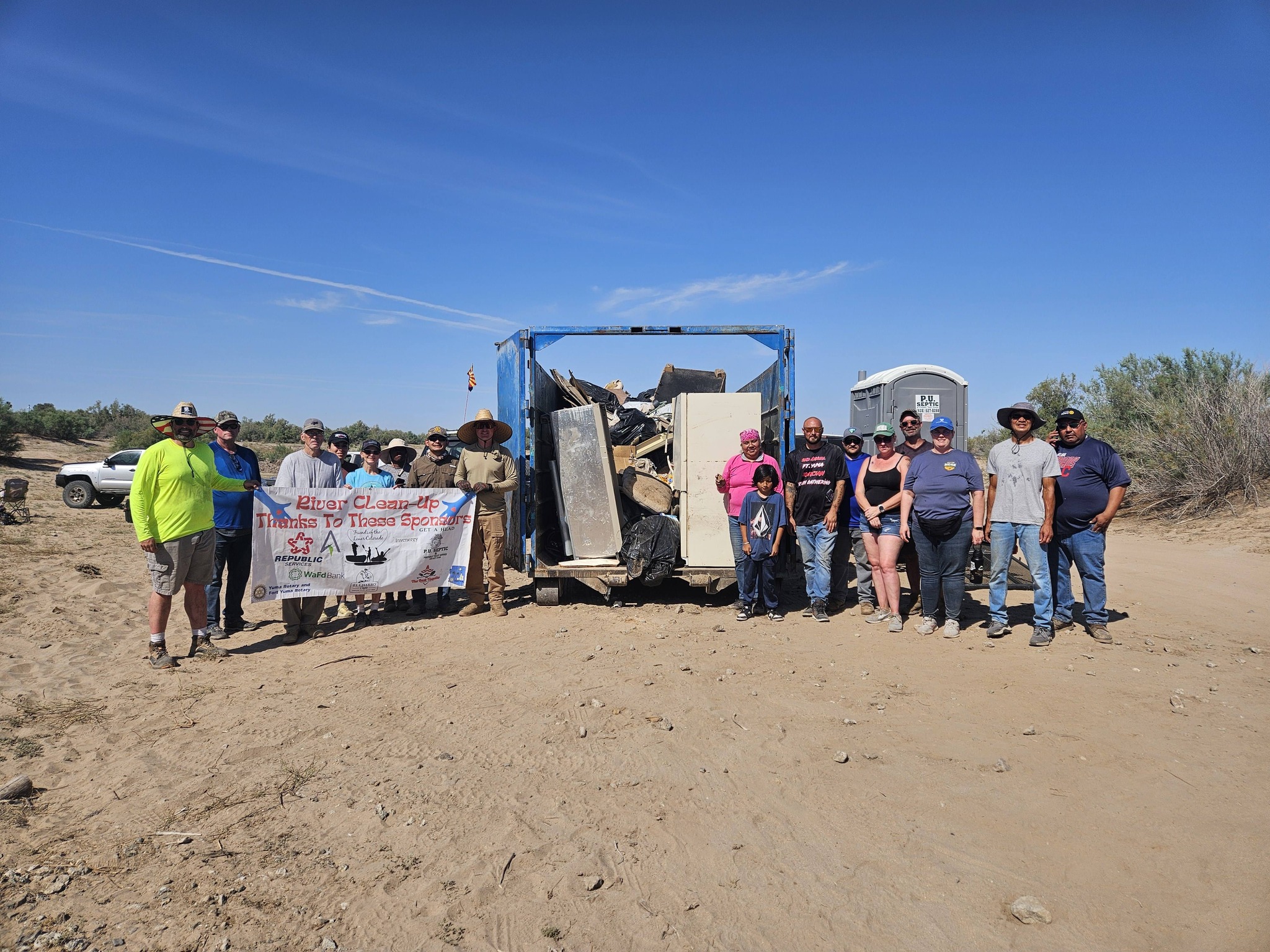 Volunteers gathered in front of a dumpster full of trash they collected